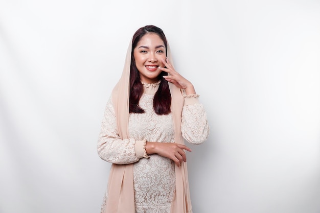 Jonge Aziatische Moslimvrouw die hoofddoek draagt die aan de camera glimlacht die door witte achtergrond wordt geïsoleerd