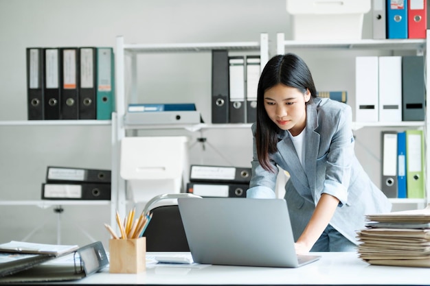 Jonge Aziatische onderneemster die op kantoor werken die laptop gebruiken