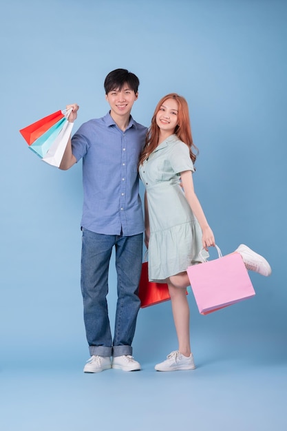 Jonge Aziatische paar dragen boodschappentas op blauwe achtergrond