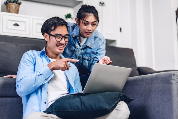 Jonge Aziatische paar ontspannen met behulp van laptop computer werken en video conferentie vergadering online chat.