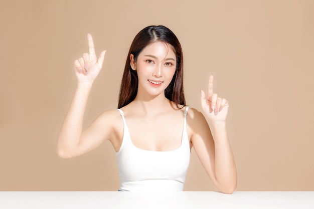 Jonge Aziatische schoonheid vrouw model lang haar met Koreaanse make-up stijl op het gezicht en perfecte huid op geïsoleerde beige achtergrond gezichtsbehandeling Cosmetologie Spa Esthetische plastische chirurgie
