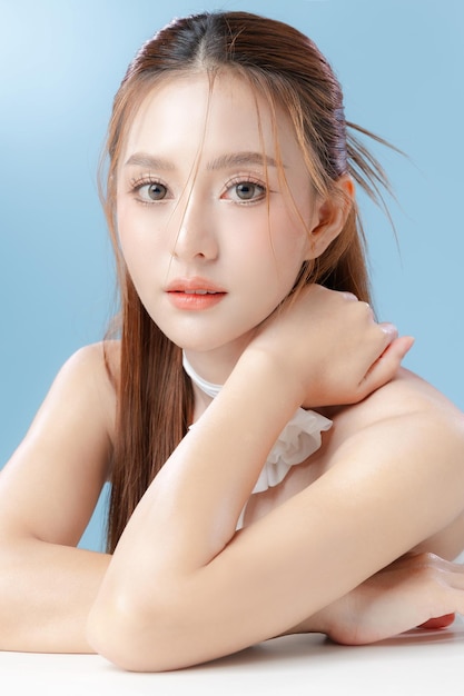 Jonge Aziatische schoonheid vrouw model lang haar met natuurlijke make-up look op gezicht en perfecte schone huid op geïsoleerde blauwe achtergrond Gezichtsbehandeling Cosmetologie Spa Esthetische plastische chirurgie