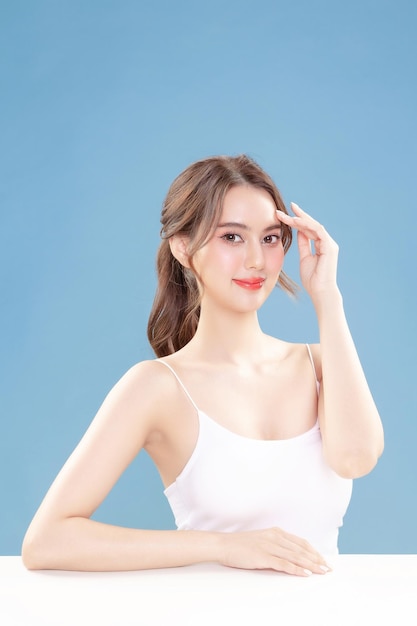 Foto jonge aziatische schoonheid vrouw trekken haar terug met koreanen make-up stijl op het gezicht en perfecte schone huid op geïsoleerde blauwe achtergrond gezichtsbehandeling cosmetologie plastische chirurgie
