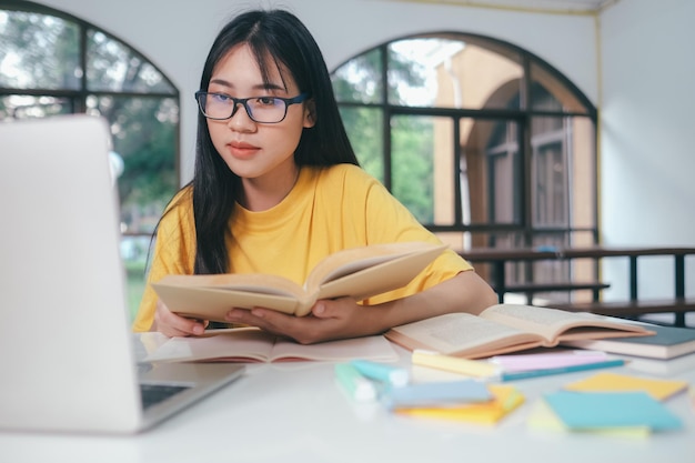 Jonge aziatische studente bereidt zich voor op het lezen van boeken voor examens aan de universiteit