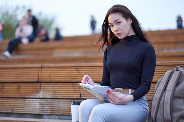 Jonge Aziatische studente die een collegeboek leest Voorbereiding van de sessie en examens buiten stadsportret