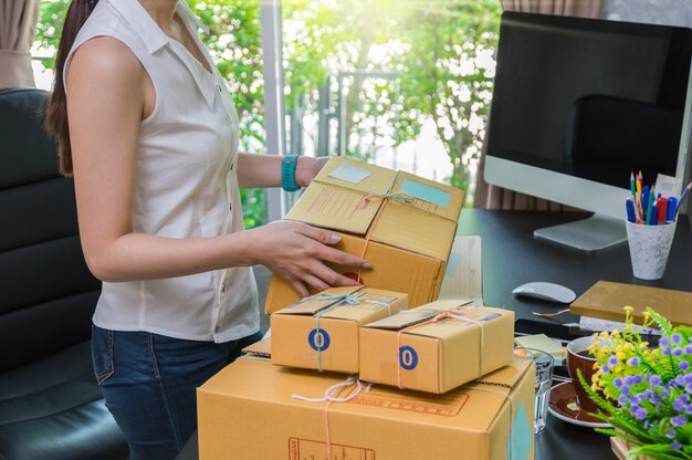 Jonge Aziatische van de tienereigenaar vrouw die een kabel bindt die pakket voorbereidt