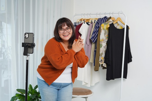 Foto jonge aziatische verkoper die een mobiele telefoon gebruikt die een bestelling ontvangt en kleding laat zien in live streaming