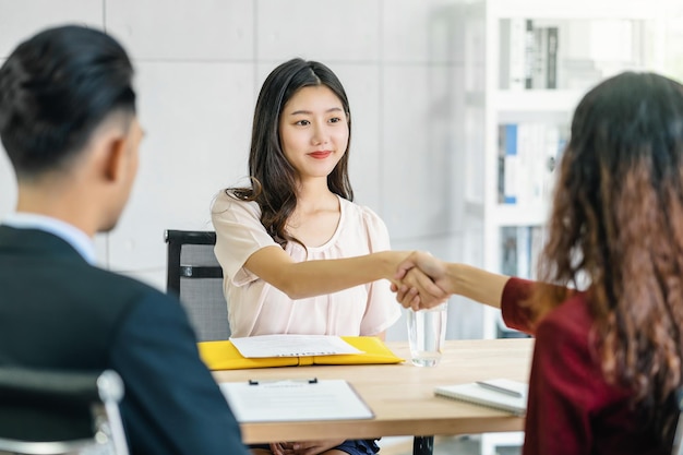 Jonge Aziatische vrouw afgestudeerde handdruk met twee manager om te verwelkomen
