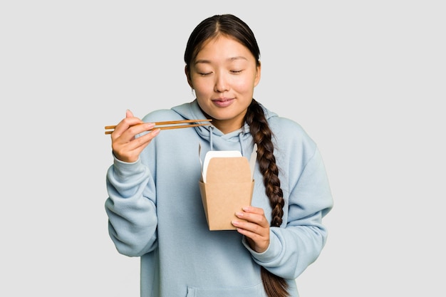 Jonge Aziatische vrouw die afhaalmaaltijden geïsoleerde ramen eet