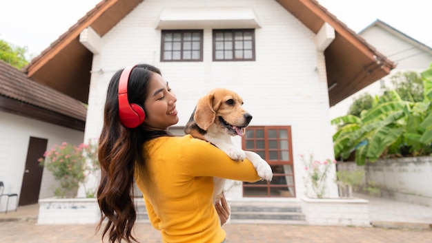 Jonge Aziatische vrouw die beagle hond vasthoudt nadat ze met de eigenaar door het huis heeft gerend tot ze uitgeput en moe is