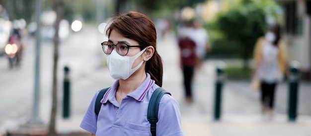 Jonge Aziatische vrouw die beschermingsmasker draagt tegen griepvirus in de stad. gezondheidszorg en luchtvervuiling concept