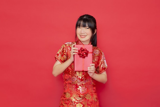 Jonge Aziatische vrouw die cheongsamkleding draagt en gift houdt