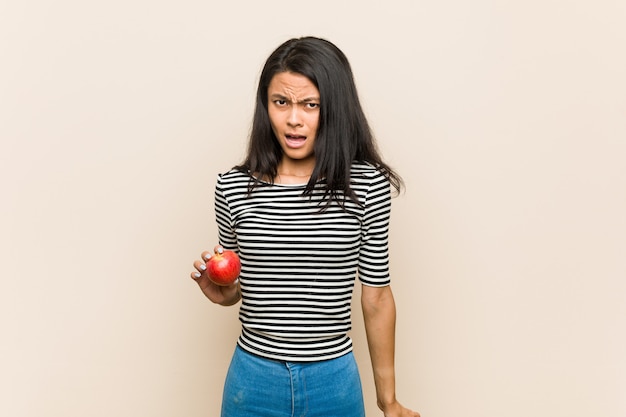 Jonge aziatische vrouw die een appel houden zeer boos en agressief gillen.