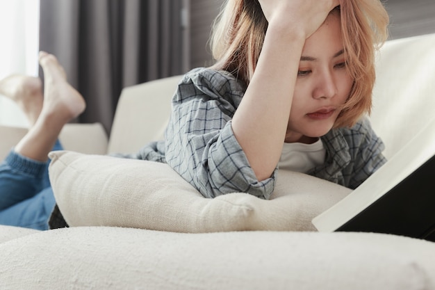 Jonge aziatische vrouw die een boek op de laag leest.