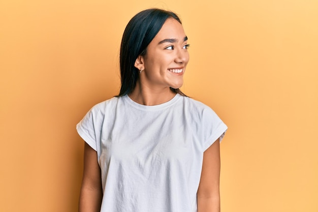 Jonge aziatische vrouw die een casual wit t-shirt draagt en naar de zijkant kijkt, ontspant profiel pose met een natuurlijk gezicht en een zelfverzekerde glimlach