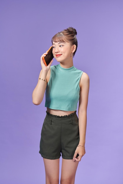 Jonge aziatische vrouw die een gesprek met de mobiele telefoon met iemand houdt