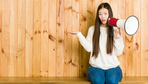 Jonge aziatische vrouw die een megafoon houden onder de indruk van het exemplaar van de holdingskopie op palm.