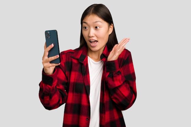 Jonge Aziatische vrouw die een mobiele telefoon geïsoleerd houdt