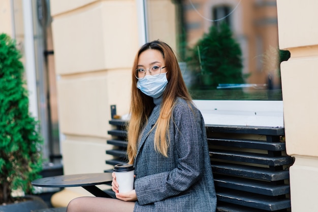 Jonge Aziatische vrouw die gezichtsmasker draagt dat zich bij een binnenlandse straat bevindt