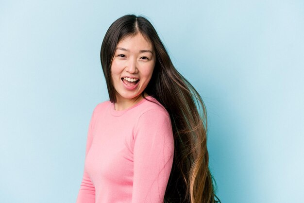 Jonge aziatische vrouw die haar beweegt dat op blauwe achtergrond wordt geïsoleerd