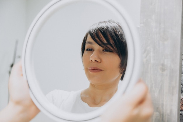 Jonge aziatische vrouw die haar gedachtengang in de spiegel bekijkt