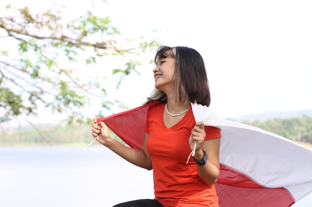 jonge aziatische vrouw die Indonesische vlag draagt