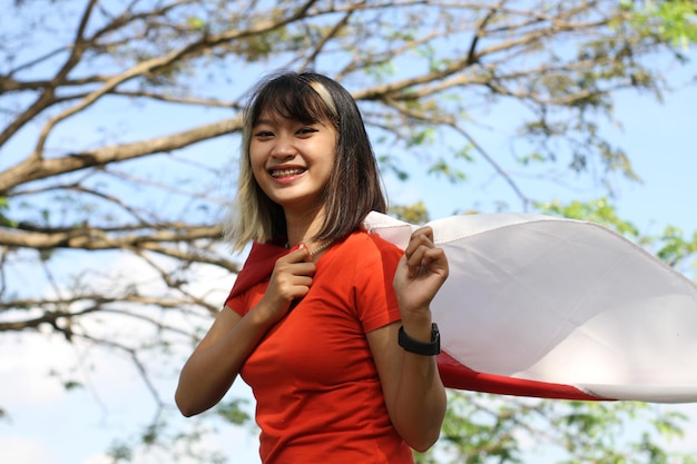 jonge aziatische vrouw die Indonesische vlag draagt