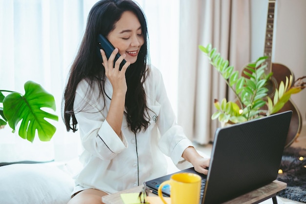 Jonge Aziatische vrouw die laptopcomputer gebruikt voor zakelijk online werk, vrouwelijke freelance die vanuit huis werkt met behulp van internet cyberspace-communicatietechnologie voor zakenvrouwen