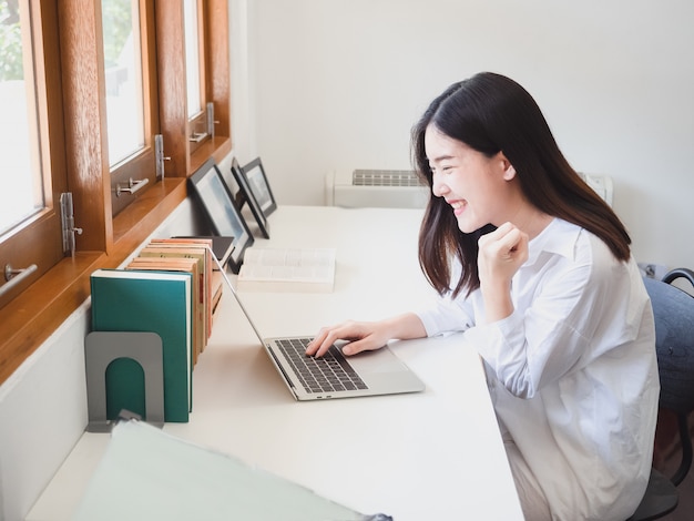 Jonge Aziatische vrouw die met computer in ruimte werkt