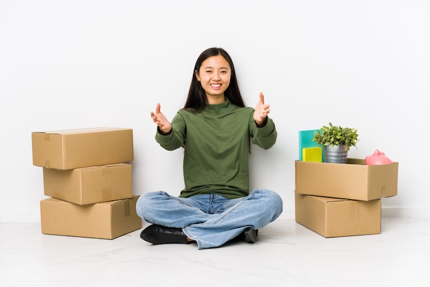 Jonge Aziatische vrouw die naar een nieuw huis verhuist, voelt zich zelfverzekerd en geeft een knuffel