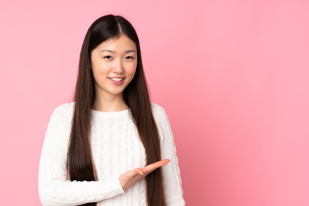 Jonge Aziatische vrouw die op achtergrond wordt geïsoleerd die een idee voorstelt terwijl het glimlachen naar kijkt