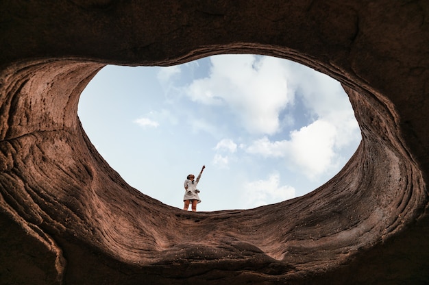 Jonge aziatische vrouw die op de grot staat en naar de blauwe lucht wijst bij Sam Phan Bok van de Grand Canyon