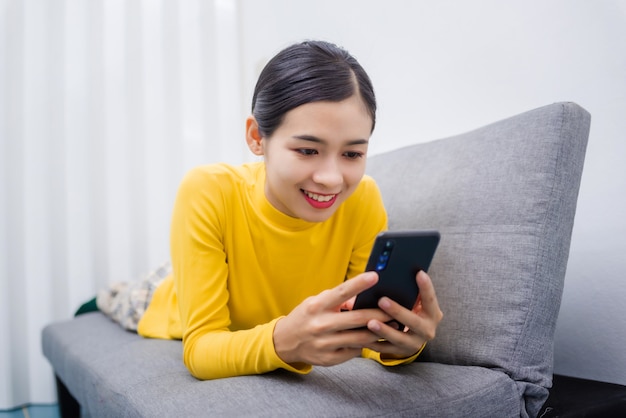 Jonge Aziatische vrouw die op iets op mobiel let