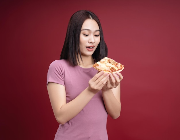 Jonge Aziatische vrouw die pizza op achtergrond eet