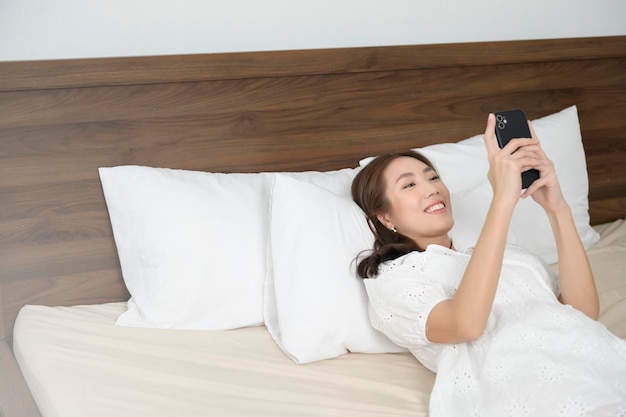 Jonge aziatische vrouw die smartphone gebruikt voor het slapengaan gelukkige levensstijl conceptx9