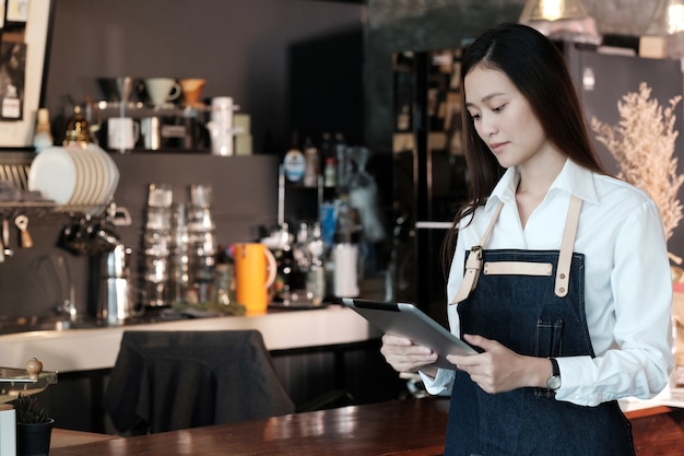 Jonge Aziatische vrouw die tablet gebruiken bij koffie