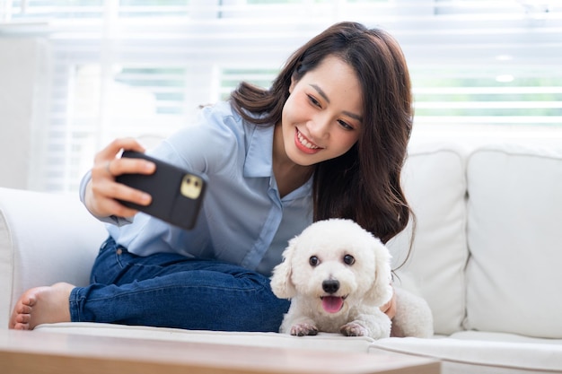 Jonge Aziatische vrouw die thuis met hond speelt