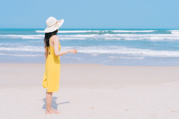 Jonge Aziatische vrouw die van de zomervakantie geniet op het strand