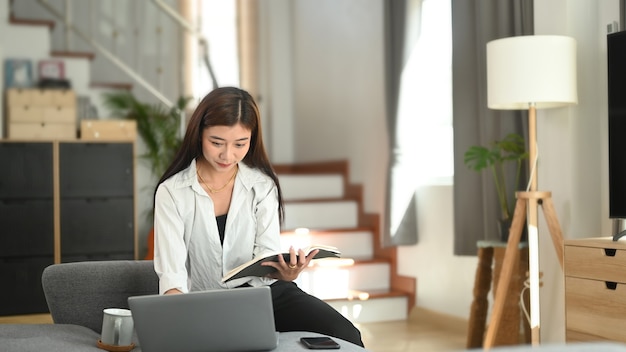 Jonge Aziatische vrouw die van huis aan laptop werkt