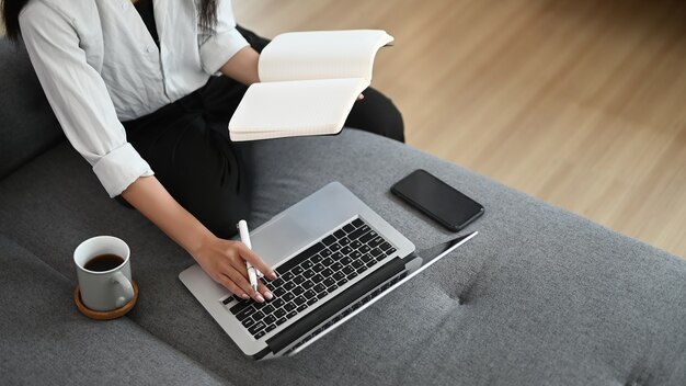 Jonge Aziatische vrouw die van huis aan laptop werkt