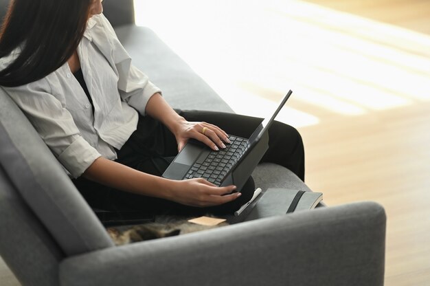 Jonge Aziatische vrouw die van huis aan laptop werkt