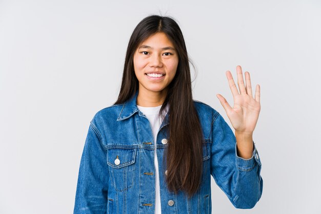 Jonge Aziatische vrouw die vrolijk tonend nummer vijf met vingers glimlacht.