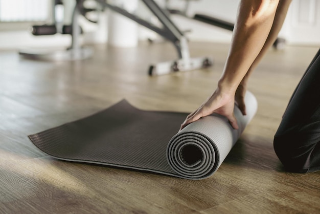 Jonge aziatische vrouw die yoga beoefent en binnenshuis mediteert in de sportschool Mooi meisje materiaal voorbereidt voor yogales kalmte en ontspanning Vrouwelijk geluk en yoga concept