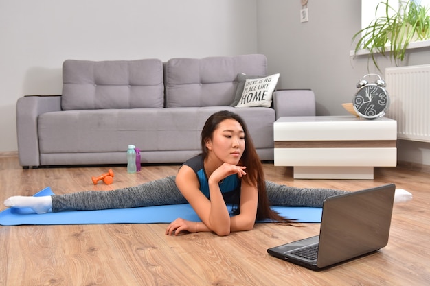 Jonge aziatische vrouw die yoga thuis maakt.