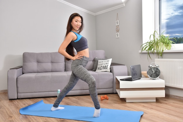 Jonge Aziatische vrouw die yoga thuis maakt.