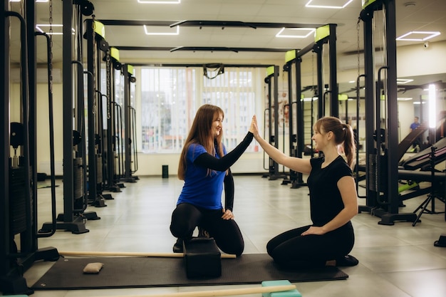 Jonge Aziatische vrouw doet beenstretches met fysiotherapeut in een persoonlijke sportschool.