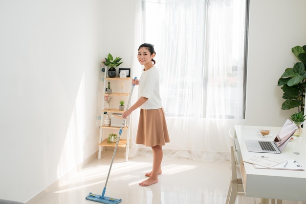 Jonge Aziatische vrouw doet schoonmaken op het kantoor aan huis.