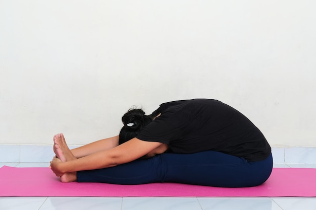 Jonge Aziatische vrouw doet yoga pose boven sportmatras