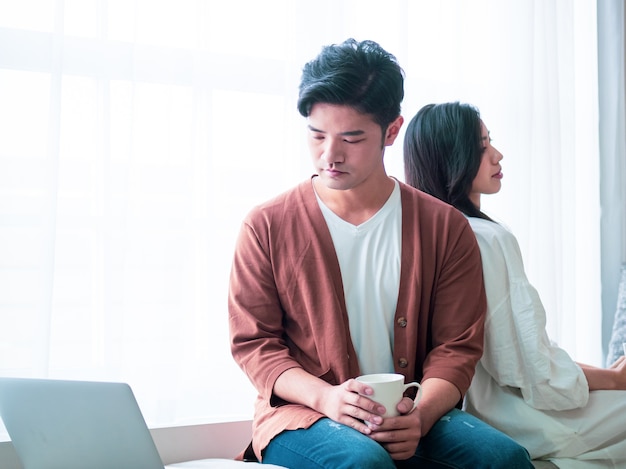 Jonge Aziatische vrouw en man thuis met kopje koffie in handen.