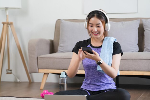 Jonge aziatische vrouw gebruikt smartphone om op internet te surfen en muziek te luisteren nadat ze thuis heeft geoefend